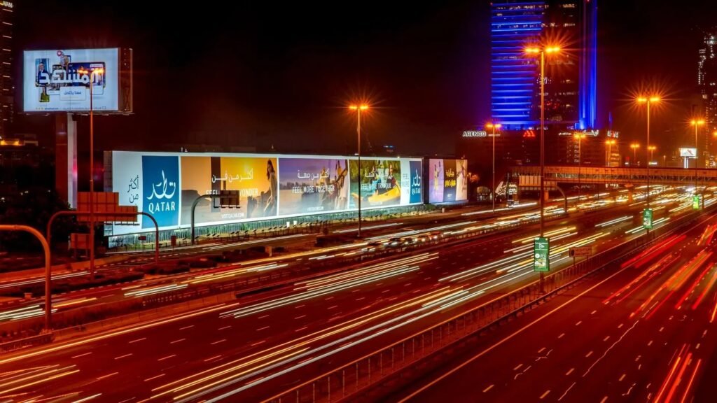 High Impact Advertising Formats showcased through large illuminated outdoor billboards along a busy highway at night, creating strong brand visibility in an urban skyline.