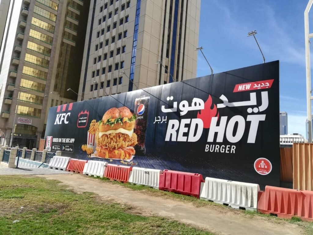 Outdoor Billboard Advertising UAE featuring a high-visibility food brand billboard near a busy city intersection