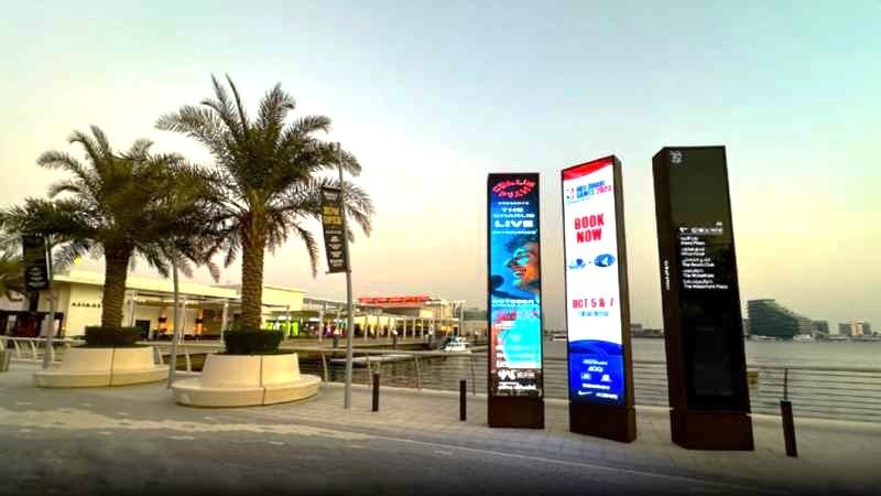 Al Ain DOOH Network showcasing vertical digital totem screens at a waterfront promenade with strong pedestrian engagement