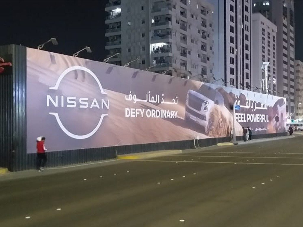 Illuminated automotive mega hoarding at night reflecting Outdoor Campaign ROI through extended visibility and scale